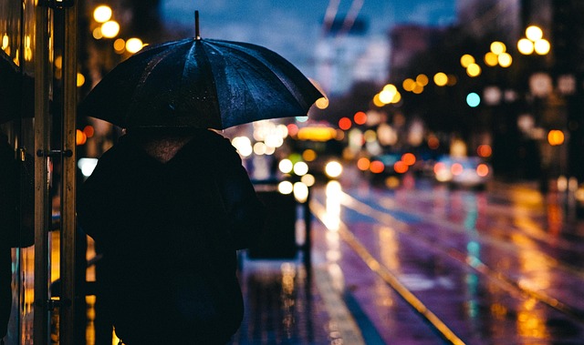 梅雨の雨に濡れた街をレインコートを着て歩く人のイメージ